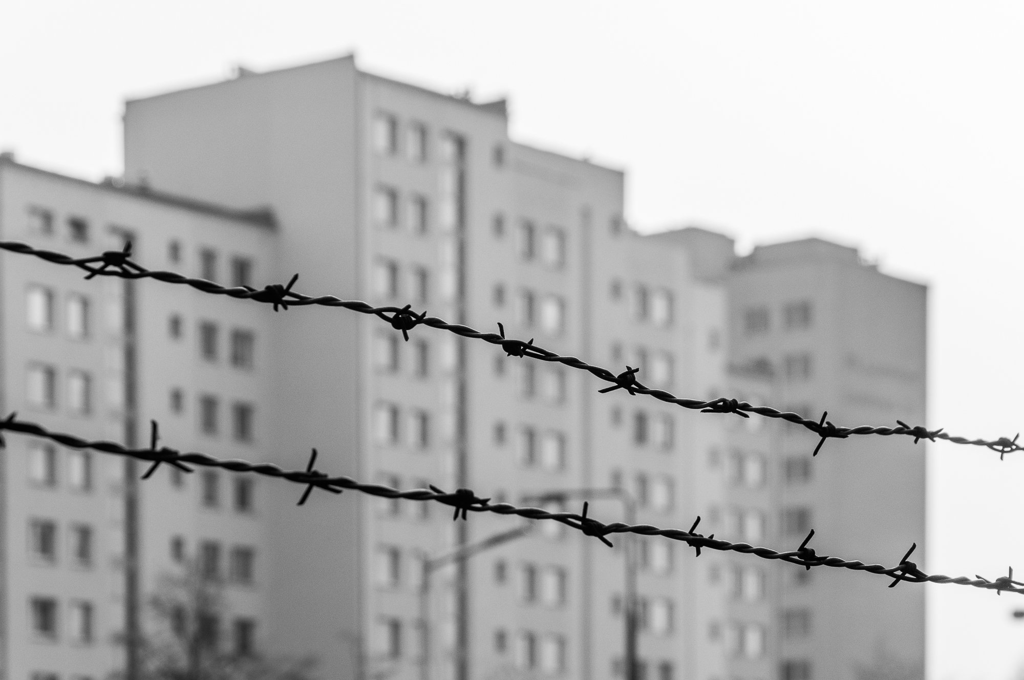 Adam Mazek Photography Warsaw 2021. Post: "How to sleep correctly?" Perspective. Barbed wire. Block of flats.